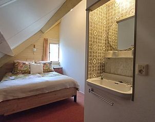 Gezellige slaapkamer in Vakantiehuisje in Tricht met wastafel en landelijke inrichting in Gelderland.