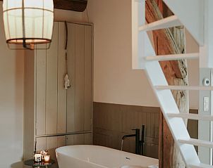 Sfeervolle badkamer in Vakantiehuisje in Altforst, Gelderland, met vrijstaand bad en rustieke houten elementen voor een ontspannen verblijf.