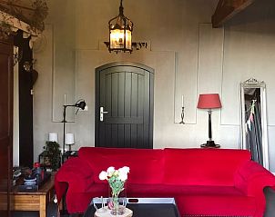 Vakantiehuisje in Buren, sfeervolle woonkamer met rode bank in Rivierengebied, Gelderland.