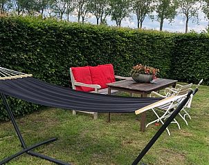 Vakantiehuisje in Buren, tuin met hangmat en zitje in het Rivierengebied van Gelderland.