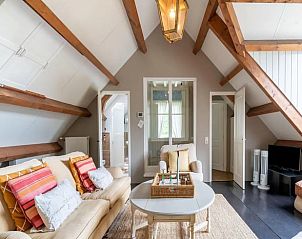 Gezellige woonkamer in Vakantiehuis in Deil, Gelderland met houten balken en comfortabele zithoek.