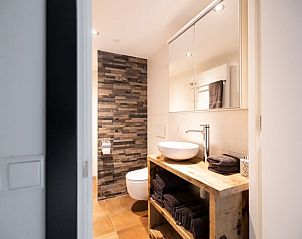 Stijlvolle badkamer met natuurstenen muur in Vakantiehuisje in Winssen, Gelderland.