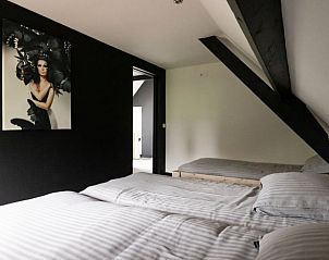 Tweepersoonsbed en kunst in slaapkamer van Vakantiehuisje in Winssen, Gelderland.