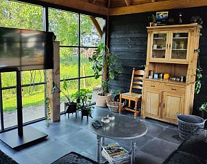 Gezellige hoek met tv in Vakantiehuisje in Herveld, Gelderland. Geniet van entertainment met uitzicht op de natuur.