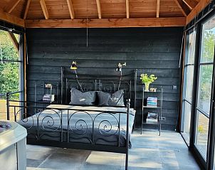 Slaapkamer met groot bed in Vakantiehuisje in Herveld, Gelderland. Ontspan in comfort met uitzicht op de tuin.