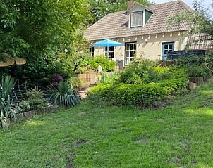 Groene tuin met terras bij Vakantiehuisje in Dreumel, perfect voor ontspanning.