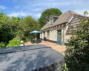 Terras met jacuzzi bij Vakantiehuisje in Dreumel, omgeven door natuur.