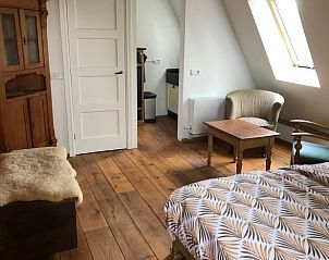 Gezellige slaapkamer in Huisje in Dreumel, vakantiehuis in Rivierengebied, Gelderland met houten vloer en comfortabele zithoek.