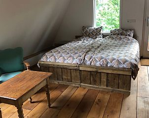 Sfeervolle slaapkamer in Huisje in Dreumel, vakantiehuis in het Rivierengebied, Gelderland, met houten vloer en uitzicht op de groene omgeving.