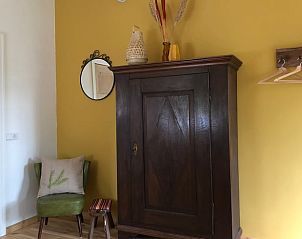 Stijlvolle inrichting in Huisje in Dreumel, vakantiehuis in het Rivierengebied met houten kast en gele muur.