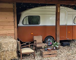 Huisje in Dreumel, Gelderland biedt een unieke vakantie-ervaring met een retro caravan en gezellige zithoek in de natuurlijke omgeving.