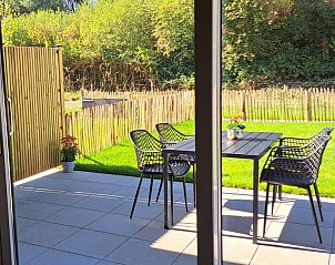 Zonnig terras bij Betuwsend vakantiehuis in Acquoy, Gelderland, met uitzicht op groene tuin en privacy biedende schutting.