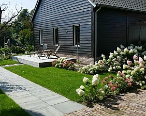 Terras van vakantiehuisje in Beusichem, omgeven door kleurrijke bloemen in Gelderland.
