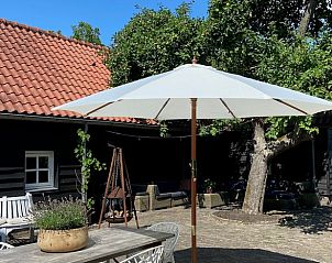 Zonnig terras bij Vakantiehuisje in Neerijnen, Gelderland, met parasol en gezellige zithoek.
