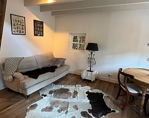 Gezellige woonkamer in Vakantiehuisje in Neerijnen, Gelderland met comfortabele bank en houten vloer.