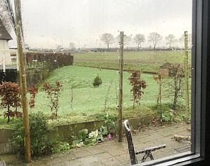 Uitzicht vanaf het terras van Huisje in Geldermalsen, vakantiehuis in Gelderland, met groene velden en landelijke charme.