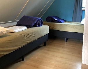 Zonnig terras van vakantiehuis DG312 in Winterswijk met groene parasol en tuin.