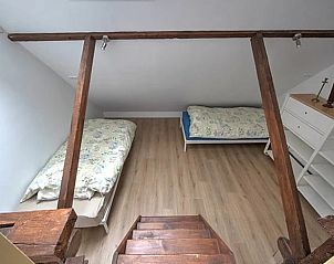 Sleeping loft in Holiday Home in Winterswijk with two single beds and wooden floor.