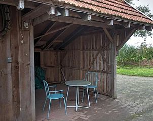 Rustic barn with seating at Holiday Home in Winterswijk, perfect for outdoor evenings.