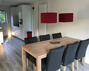 Dining room in Holiday Home in Winterswijk, Achterhoek, with stylish wooden table and comfortable chairs.