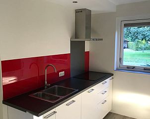 Modern kitchen in Holiday Home in Winterswijk, Achterhoek, with red accents and garden views.
