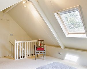 Lichte slaapkamer met stoel en dakraam in Huisje in Barchem, Gelderland.