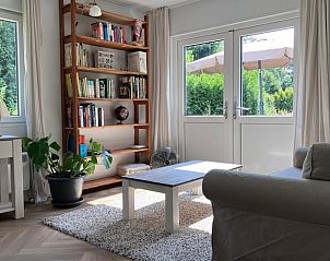 Gezellige woonkamer in vakantiehuisje in Barchem met boekenplank en uitzicht op de tuin in de Achterhoek.