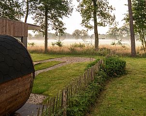 Enjoy the serene garden and sauna at Holiday Villa Boslodge 2 in Kotten, Achterhoek, surrounded by misty nature and tranquil views.