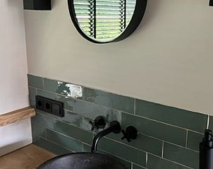 Moderne badkamer met ronde spiegel in Vakantiehuis in Heelweg, Achterhoek, Gelderland.