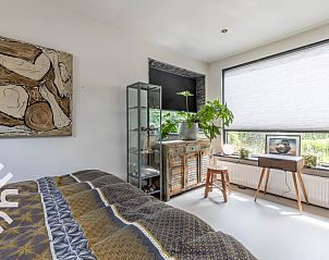 Zijaanzicht van DG1611 vakantiehuis in Heelweg, Achterhoek, met bloeiende tuin en boomhut.