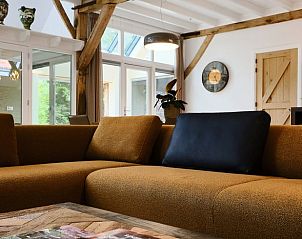 Gezellige woonkamer van Vakantiehuisje in Zelhem, Achterhoek, met houten balken en comfortabele bank voor een ontspannen verblijf in Gelderland.