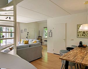 Gezellige woonkamer met open keuken in Vakantiehuis in Zelhem, Achterhoek, Gelderland. Comfortabele zithoek en houten eettafel.