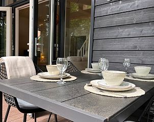 Gezellige veranda van Huisje in Ruurlo, vakantiehuis in de Achterhoek, Gelderland, met stijlvol gedekte tafel voor een ontspannen buitenmaaltijd.