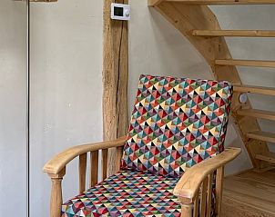 Gezellige binnenruimte van Huisje in Aalten, Achterhoek, met kleurrijke stoel en houten trap in vakantiehuis in Gelderland.