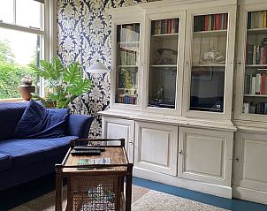 Gezellige leeshoek in Vakantiehuisje in Laren, Achterhoek, met boekenkast en bank.