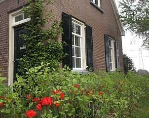 Charmant Vakantiehuisje in Lochem, Gelderland omgeven door kleurrijke bloemen en groene natuur.