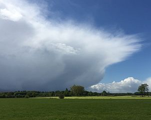 Imposante wolkenformaties boven weiland bij Vakantiehuisje in Lochem, perfect voor natuurliefhebbers.