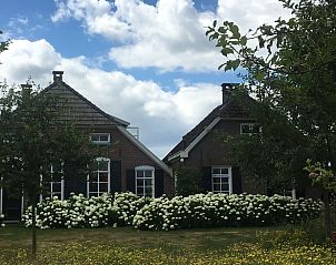 Traditionele architectuur van Vakantiehuisje in Lochem, omgeven door bloeiende hortensia's.