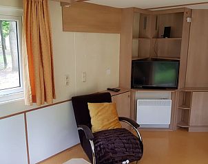 Gemtliches Wohnzimmer von Huisje in Lochem, Ferienhaus in Achterhoek, Gelderland, mit bequemem Sessel und modernem Fernseher.