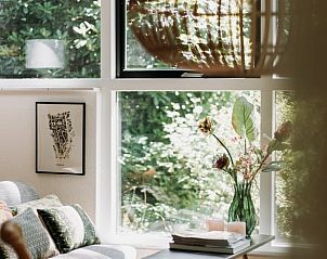 Lichte zithoek in vakantiehuis in Lochem met uitzicht op het groene bos.