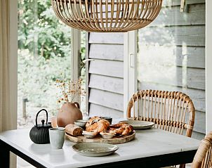 Ontbijttafel in vakantiehuis in Lochem met uitzicht op de groene tuin.