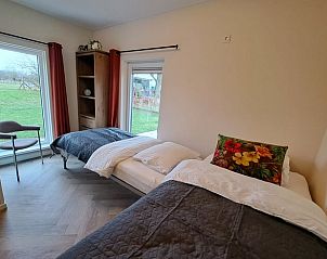 Tweepersoonsbed in Vakantiehuisje in Lochem met uitzicht op de groene omgeving van de Achterhoek, Gelderland.