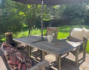 Buitenterras van Vakantiehuis in Lochem met houten tafel en parasol in de Achterhoek, Gelderland.