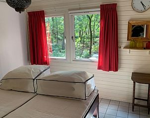 Slaapkamer met uitzicht op het bos in Vakantiehuis in Harfsen, ideaal voor ontspanning.