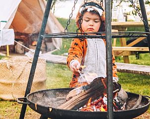 Kind geniet van het kampvuur bij Vakantiehuis in Haarlo, Achterhoek, Gelderland in een speelse outfit.