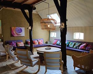 Gezellige binnenruimte van Huisje in Neede, vakantiehuis in Achterhoek, Gelderland, met kleurrijke kussens en houten interieur.