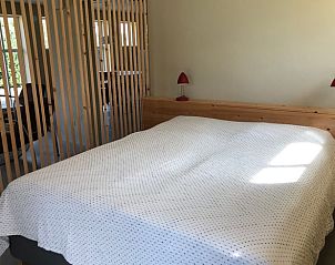 Huisje in Almen, vakantiewoning in de Achterhoek, Gelderland. Slaapkamer met houten bedframe en veel natuurlijk licht.
