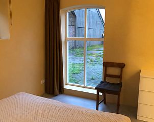 Huisje in Almen, vakantiehuis in de Achterhoek, Gelderland. Slaapkamer met uitzicht op de tuin en comfortabele stoel.