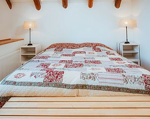 Knusse slaapkamer met kleurrijk dekbed in Vakantiehuis in Winterswijk Woold, ideaal voor een gezellige vakantie in de Achterhoek.