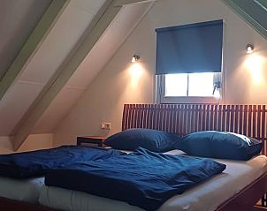 Knusse slaapkamer met houten bed in vakantiehuis in Winterswijk Woold, rustgevende sfeer in Gelderland.